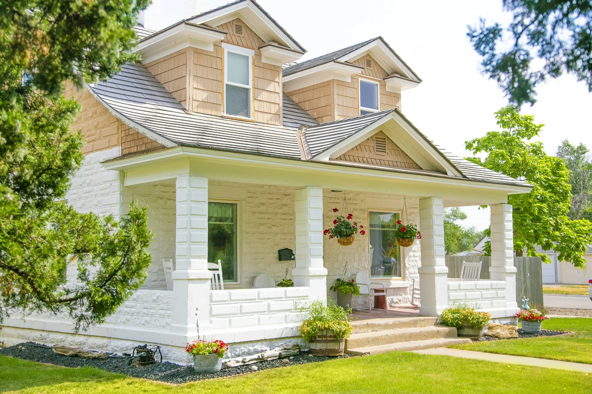 Cream house with a wide front porch and stone columns