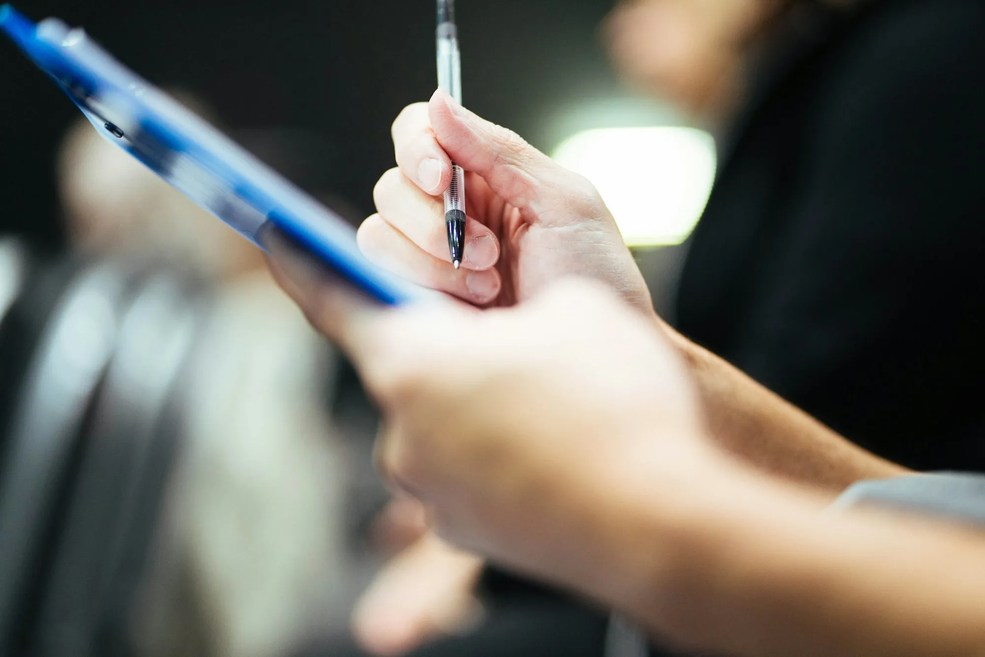 Hand holding a pen over a blue clipboard