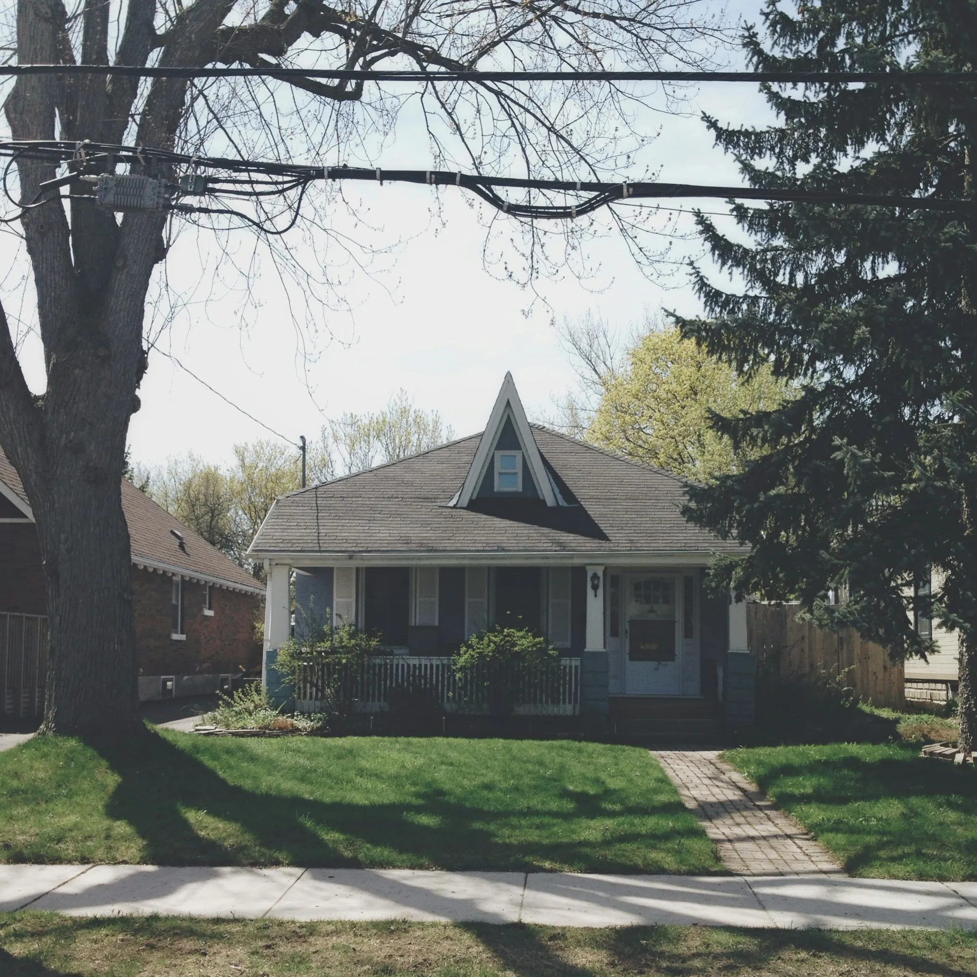 Small bungalow with a steep gable and tall trees