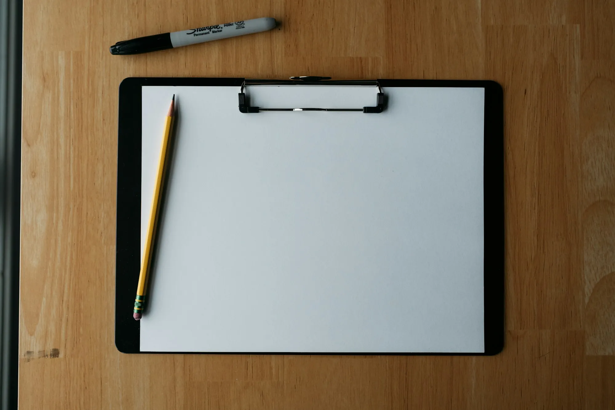 Blank clipboard and pencil on a wooden table