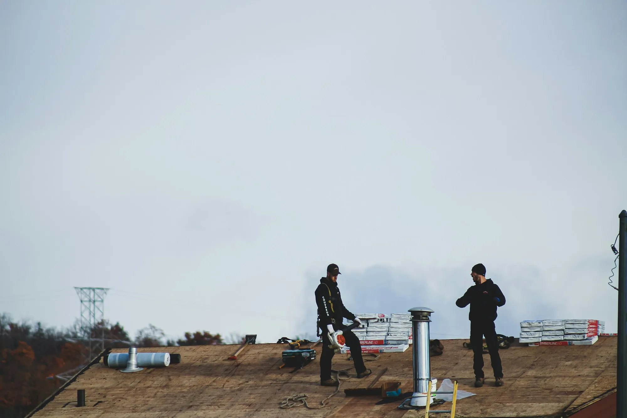 Two roofers standing on a bare roof deck during a tear-off